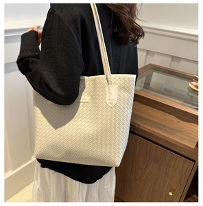 Detail of cream woven leather tote bag showing intricate braided texture and shoulder strap