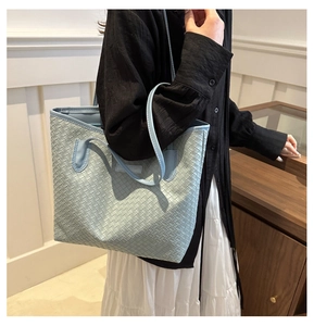 Detail of light blue woven tote bag with intricate intrecciato texture and double straps