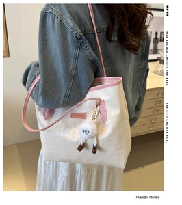 Dettaglio borsa tote in tela con bordo rosa, trama pied-de-poule e ciondolo di peluche