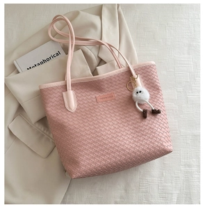 Detailed view of pink woven leather tote bag with fashion label and plush charm