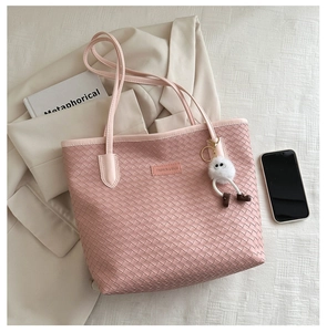 Detailed texture of pink woven tote bag with fashion label and white fluffy keychain