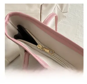 Dettaglio della cerniera dorata liscia e del bordo rosa sulla borsa tote beige