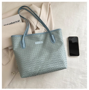 Macro detail of the woven leather texture and fashion logo on this blue tote bag