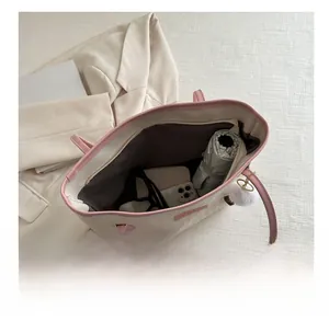 Vista dall'alto dell'interno della borsa tote beige che mostra la capienza e gli oggetti