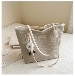 Close-up of woven tote bag texture with fashion label and soft plush ball charm