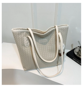 Detail of beige woven tote bag with FASHION & BAGS leather label and plush charm