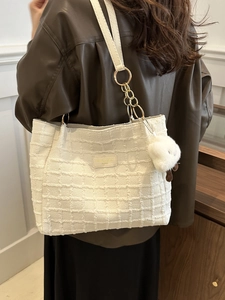 White tweed tote bag with chain strap and lamb charm shown on model's shoulder