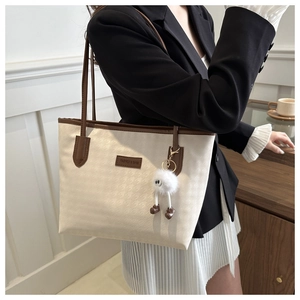 Dettaglio della borsa tote pied-de-poule con finiture in pelle marrone e ciondolo peluche