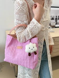 Pink textured tote bag with cloud charm shown on model in a minimalist setting