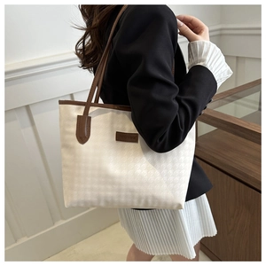 Dettaglio della borsa tote crema con trama pied-de-poule e finiture in pelle marrone