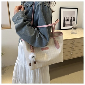 Dettaglio della borsa tote pied-de-poule con tracolla rosa e ciondolo a pompon