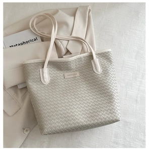Detailed view of woven texture and brand label on a beige large capacity tote bag
