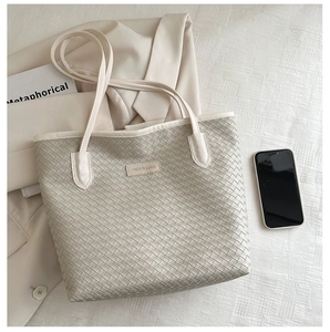 Detail of woven tote bag showing texture, long leather straps and logo label