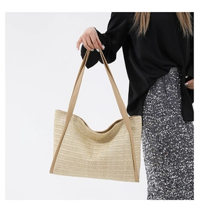 Detail of beige woven straw tote bag with smooth brown shoulder straps on a model