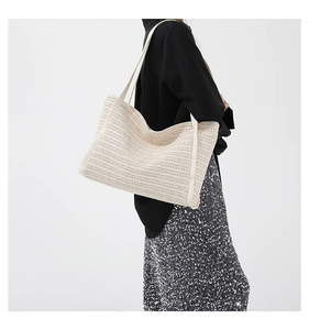 Detail of off-white straw woven tote bag with white ribbon straps on model