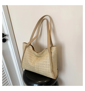 Detailed view of beige straw tote bag featuring dense horizontal weaving and brown leather straps