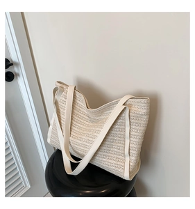 Close-up of a striped woven tote bag with soft leather handles on a minimal black stool