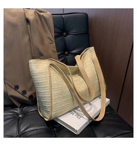 Detail view of woven straw tote bag with brown leather straps on an elegant office chair