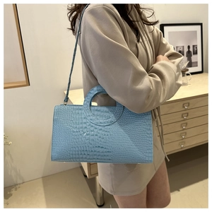 Dettaglio borsa a mano azzurra con motivo coccodrillo e design unico del manico rotondo
