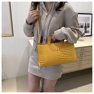 Detail of yellow crocodile embossed handbag with unique circular handle and strap