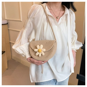 Detailed close-up of handmade straw woven saddle bag featuring a white 3D daisy flower