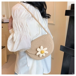 Detail of hand-woven straw saddle bag with a white daisy flower on a summer beige finish