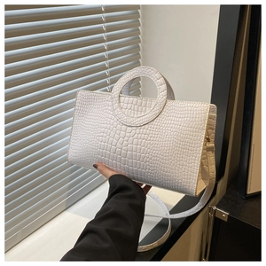 Detail of white crocodile embossed rectangular handbag with a round handle and slim strap
