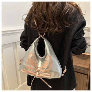 Détail du sac Y2K argenté avec papillon rose et finitions de rubans entrelacés