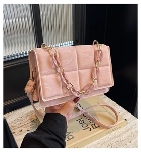 Detail view of pink textured leather bag with chunky acrylic chain and golden hardware