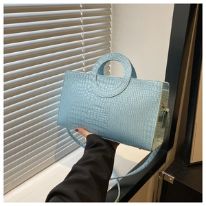 Detail of light blue croco-embossed handbag with unique circular cutout handle
