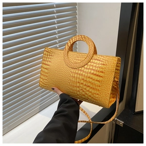 Detail of orange crocodile pattern bag featuring unique circular hollow handle design