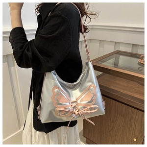 Bolso de hombro plateado metalizado con lazo de mariposa rosa y detalles de cordones