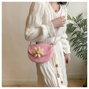 Detail of pink woven straw saddle bag with a 3D daisy flower on white dress