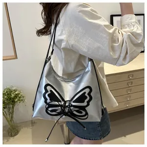 Detail of silver metallic hobo bag featuring large black butterfly patch and ribbon tie