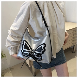Détail du sac argenté métallisé orné d'un grand nœud papillon noir et blanc tendance