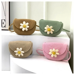 Detail of colorful hand-woven straw crossbody bags with white daisy floral ornaments