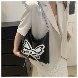 Détail du sac sous l'aisselle noir avec broderie papillon argentée et nœuds décoratifs