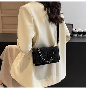 Sac bandoulière noir matelassé avec chaîne dorée porté par un mannequin en gros plan