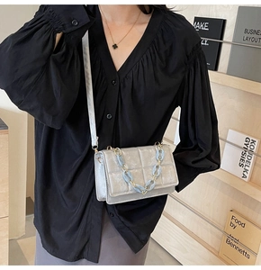 Close-up of silver-grey quilted crossbody bag with stylish chain detail on model