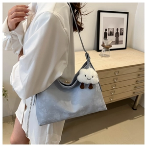 Detail of light blue matte bucket bag with white cloud plush pendant and silver chain