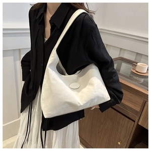 Minimalist white PU leather hobo bag worn as a shoulder bag in a stylish urban setting