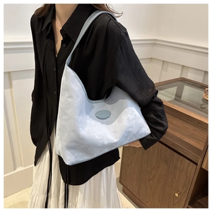 Macro detail of light blue tote bag featuring cloud texture and oval logo on the side