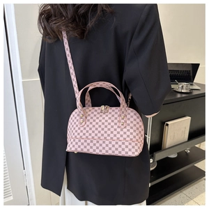 Detail of pink Boston shell bag with geometric patterns worn over a black blazer