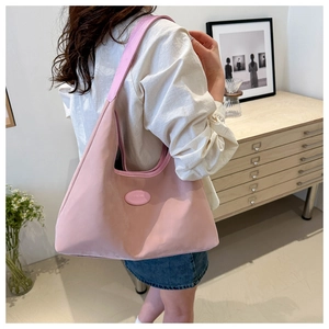Detail view of pink nylon hobo shoulder bag worn by model in minimalist indoor setting