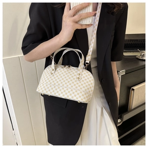 Detail view of white vintage shell bag with gold circle pattern and protective base studs
