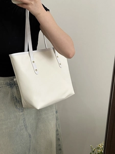 Grand sac fourre-tout blanc avec rivets dorés porté à l'épaule pour un style chic