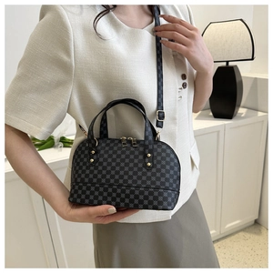 Detail of dark grey shell bag with geometric patterns and golden metal hardware