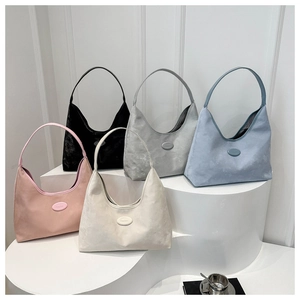 Group shot of five colorful suede hobo shoulder bags displayed on minimalist white stairs