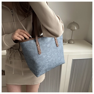 Detailed view of large blue tote bag with brown leather handles and metal rivets