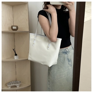 Détail du sac cabas en cuir blanc avec rivets dorés dans un décor chaleureux